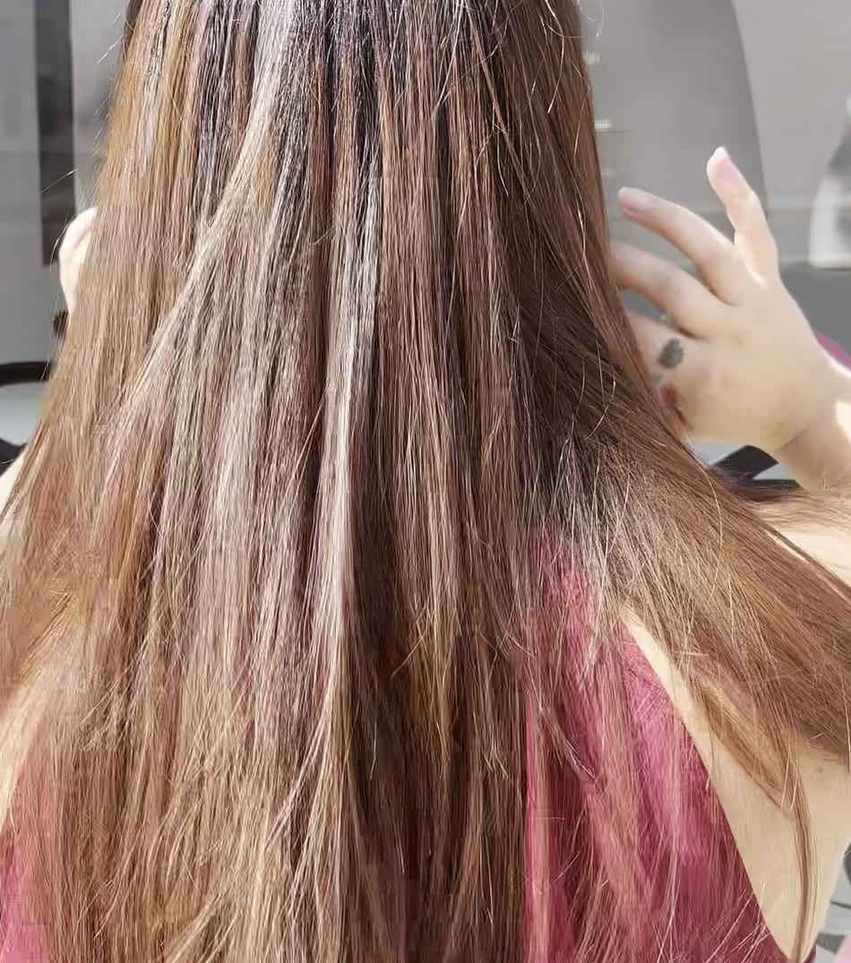 Manos del equipo trabajando con mimo una melena larga con ondas en el salón